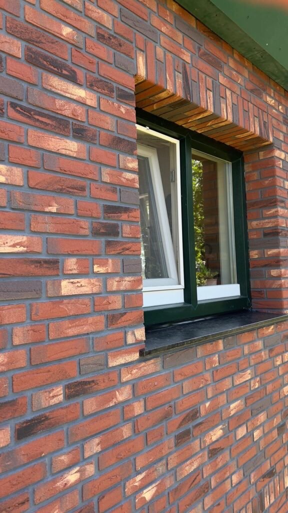 Gevel met minerale steenstrips rond een raamkozijn