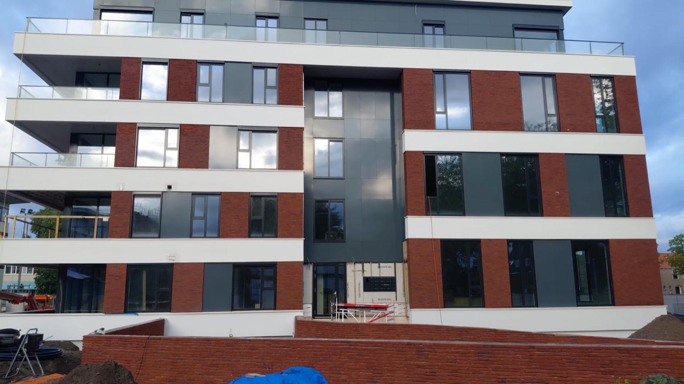 Appartementengebouw in Emmeloord met vlakken van rode steenstrips, witte sierpleister, antraciet panelen en balkons met glazen balustrades