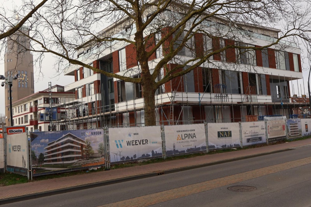 Hoekzijde van het appartementengebouw in Emmeloord tijdens de uitvoering, met steigers en bouwhekken
