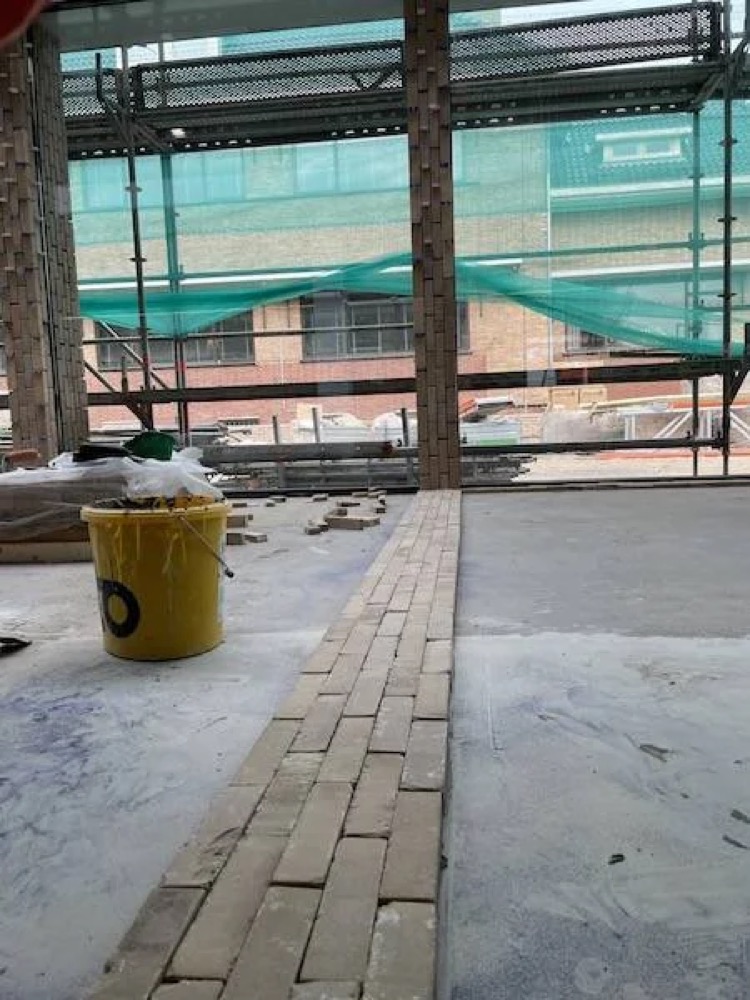 Baksteenvloer die wordt gelegd in de glazen hal van het gemeentehuis van Katwijk