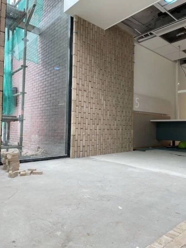 Steenstripswand naast een net gelegd deel van de vloer in het gemeentehuis van Katwijk
