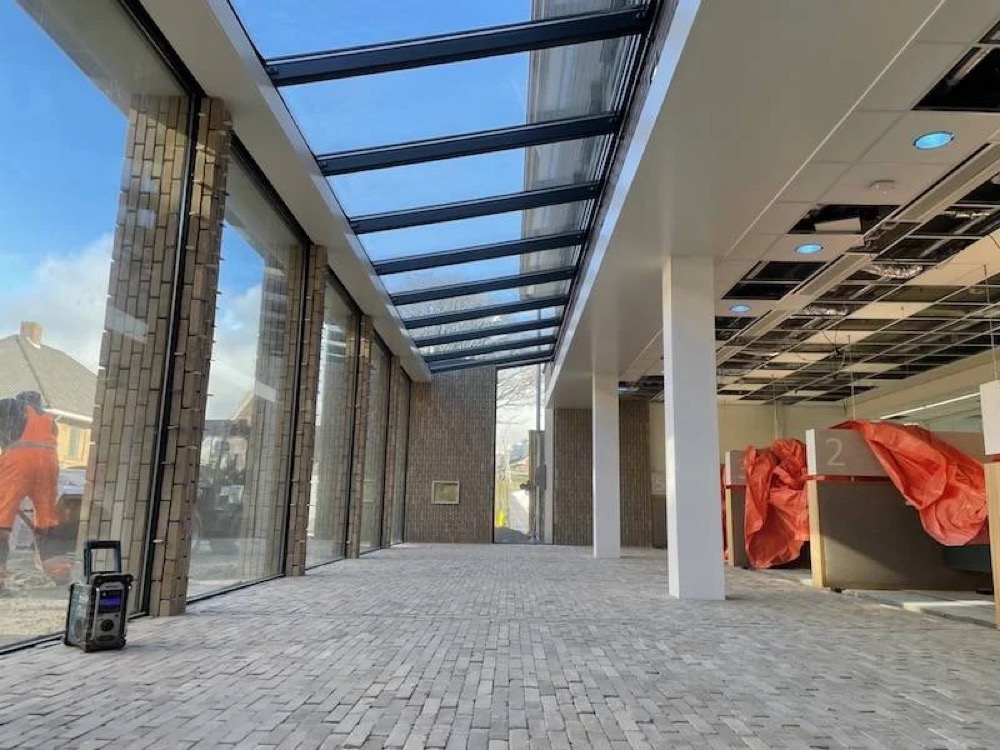 Afgewerkte baksteenvloer onder het glazen dak van het gemeentehuis van Katwijk