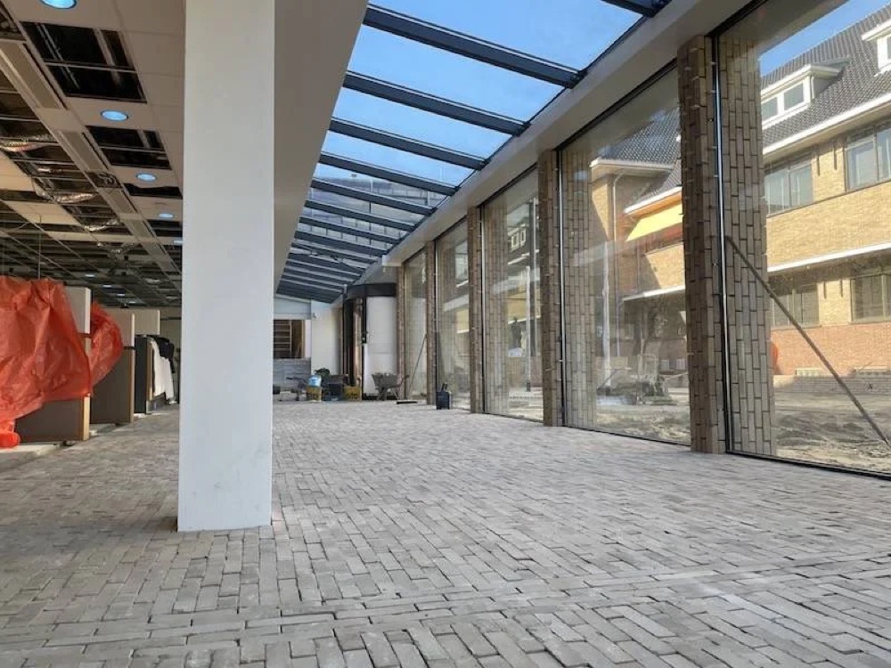 Afgewerkte hal met betonnen kolommen en glaswanden bij het gemeentehuis van Katwijk