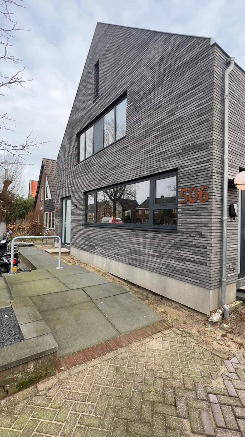 Voormalige bakkerij in Heiloo, nu woonhuis: puntgevel en langsgevel met gemêleerd grijze steenstrips en nieuwe kozijnen