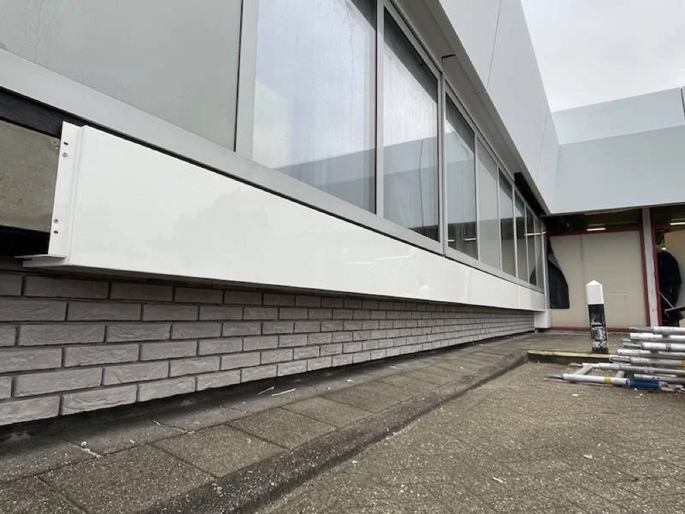 Lichte steenstrips onder een witte gevelpartij met glas bij het Noordwest Ziekenhuis in Den Helder