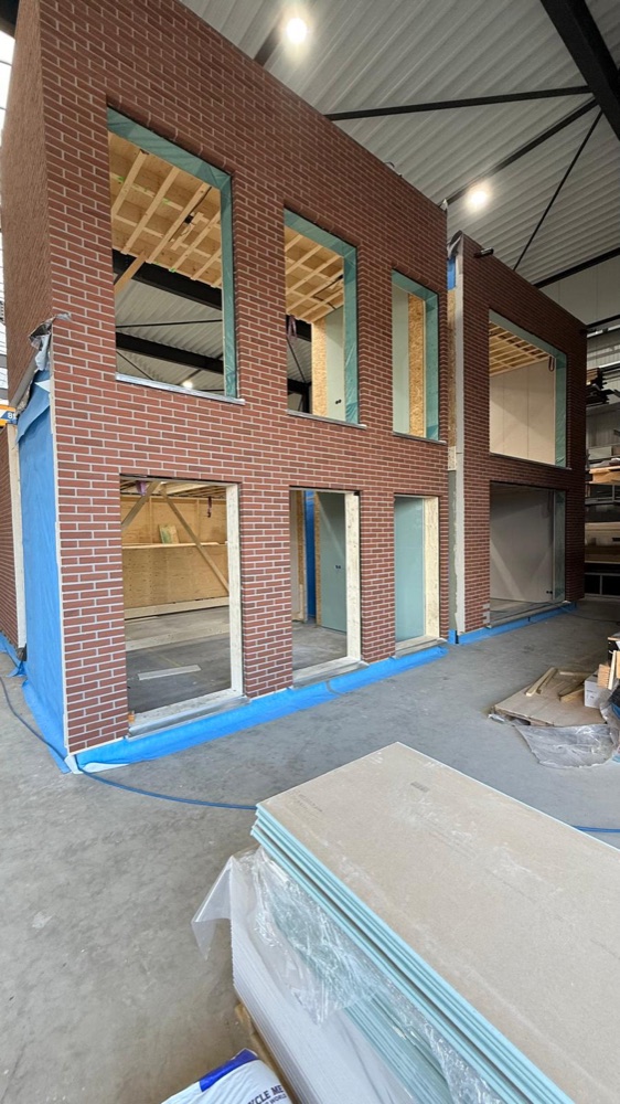 Prefab module van twee lagen met rode minerale steenstrips en raamopeningen