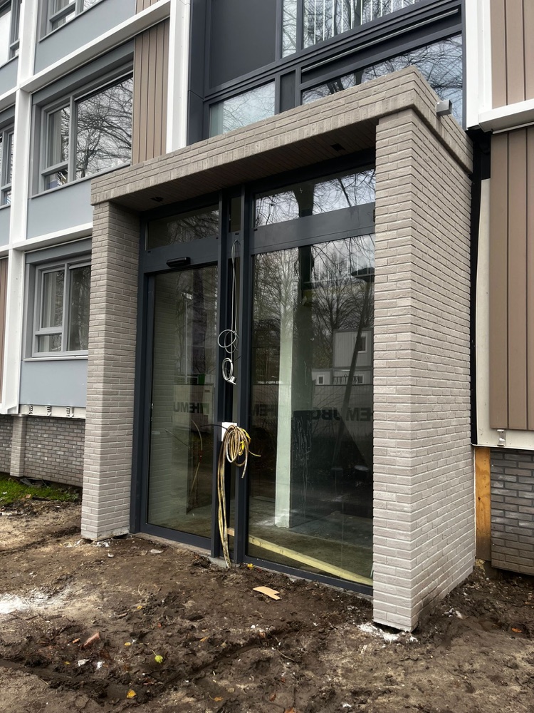 Entree van een traphuis in Utrecht met lichtgrijze minerale steenstrips, schuin van opzij gezien
