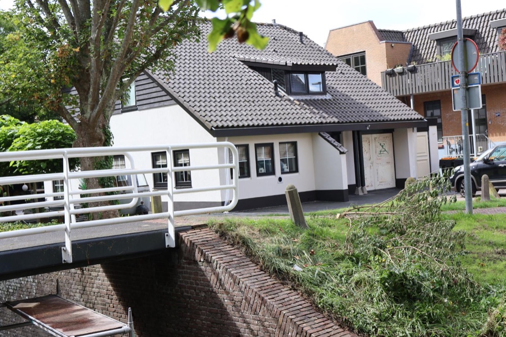 Villa in Koedijk met witte gevel, gezien vanaf een bruggetje over de sloot