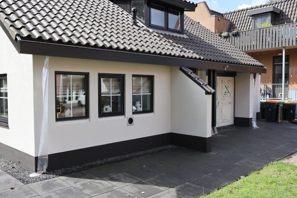 Zijgevel van de villa in Koedijk met witte sierpleister en een antraciet plint