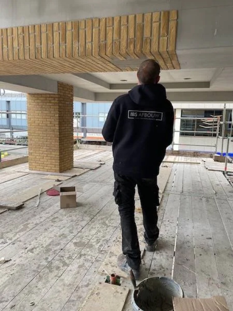Een man loopt onder het met steenstrips bekleedde plafond en de kolom bij het winkelcentrum in Haarlem