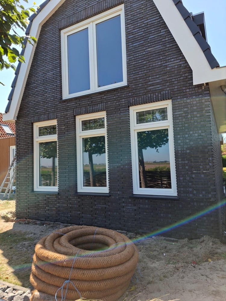 Gevel van de woning in Julianadorp met donkere steenstrips en drie witte kozijnen
