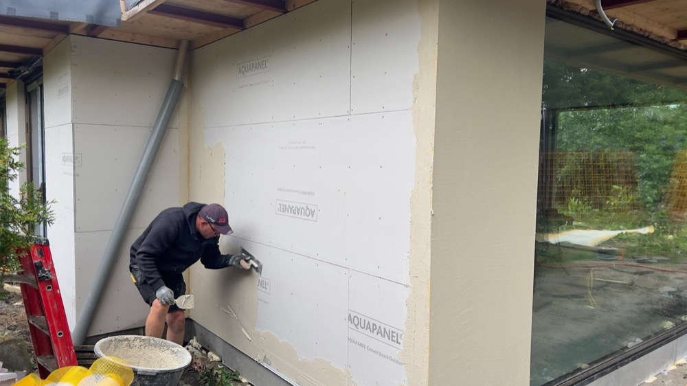 Vakman werkt de mortellaag af op Aquapanel-cementplaten als gevelondergrond bij een woonhuis in Amsterdam-Noord