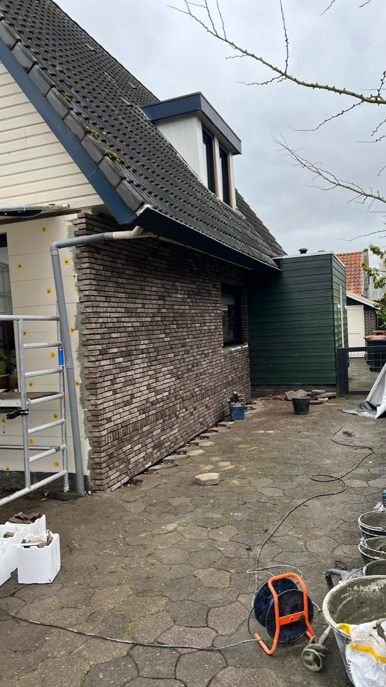 Afgewerkt woonhuis in Andijk met donkere kap, een gevel van gemêleerd bruine steenstrips en een groene voortuin