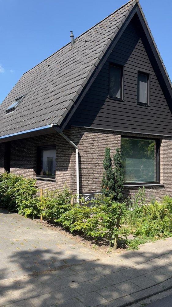 Voorzijde van het woonhuis in Andijk met donkere kap en steenstripsgevel