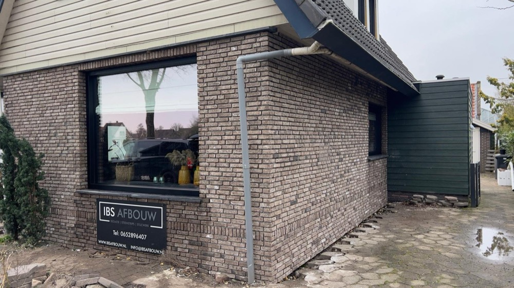 Afgewerkte gevel met raam en een bord van IBS Afbouw bij het woonhuis in Andijk