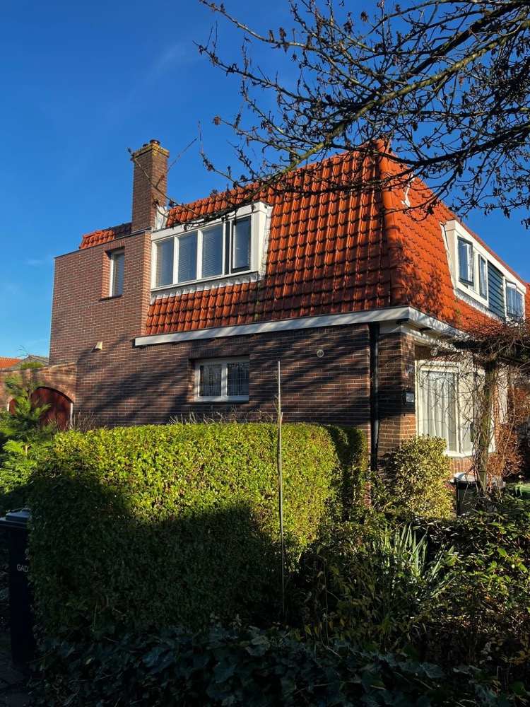 Woonhuis in Bussum met een kopgevel van donkere minerale steenstrips, dakkapel en oranje dakpannen