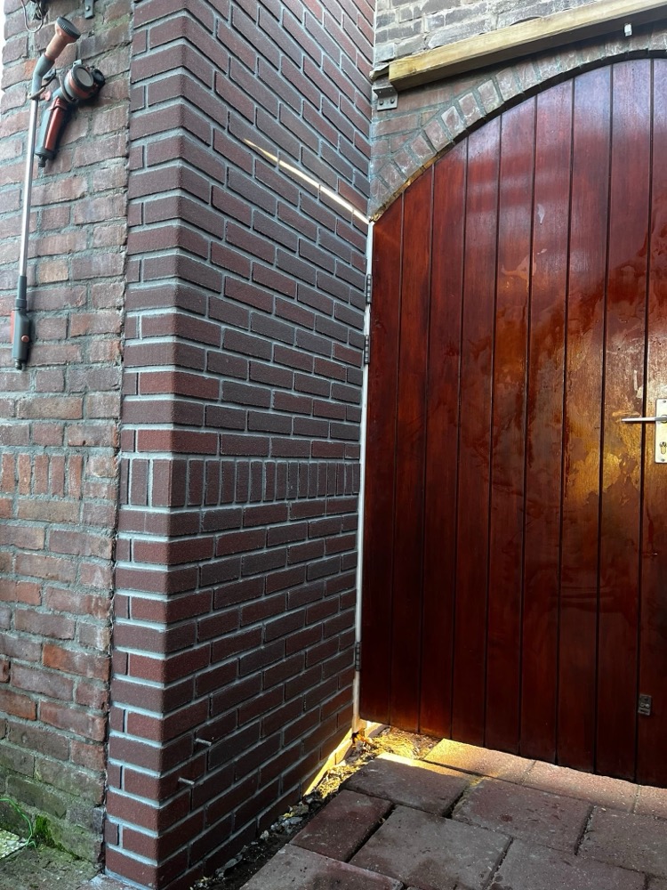 Donkere steenstripsgevel naast een houten poort in Bussum