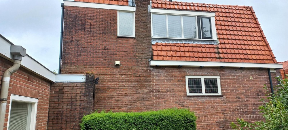 Kopgevel van een woonhuis in Bussum vóór de werkzaamheden: verweerd baksteen met vochtplekken