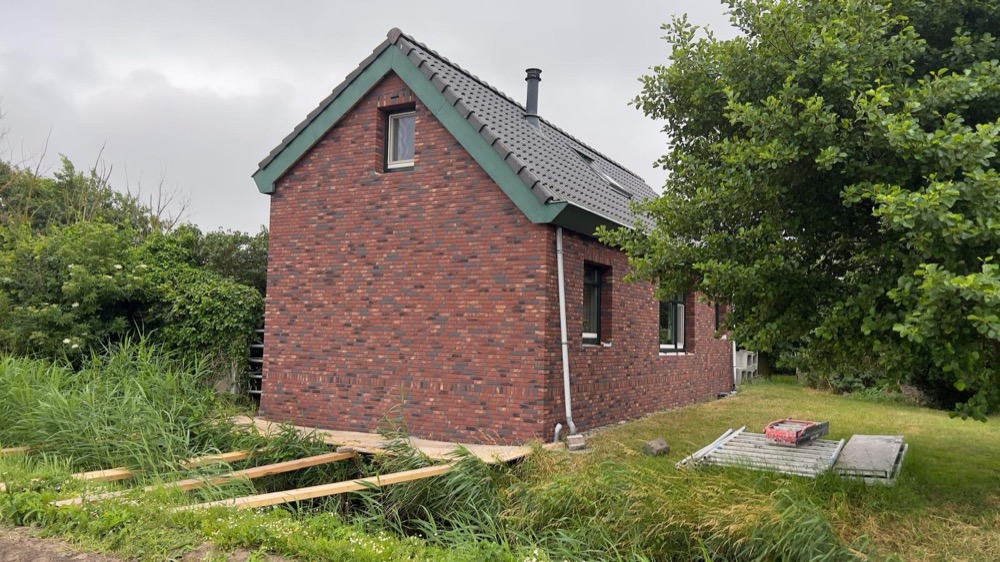Afgewerkte gevel met minerale steenstrips bij een woonhuis in Callantsoog