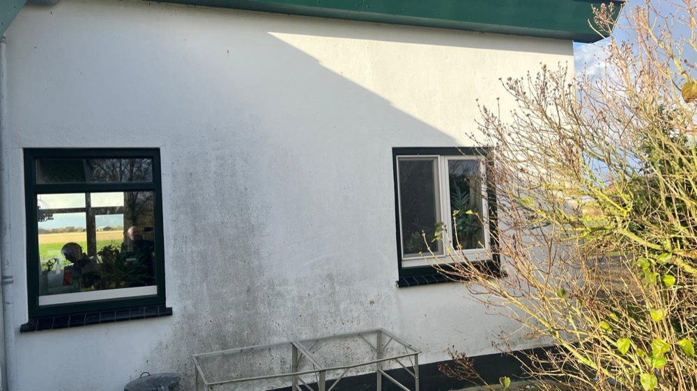 Oorspronkelijke witte gevel met een zwart kozijn bij het woonhuis in Callantsoog