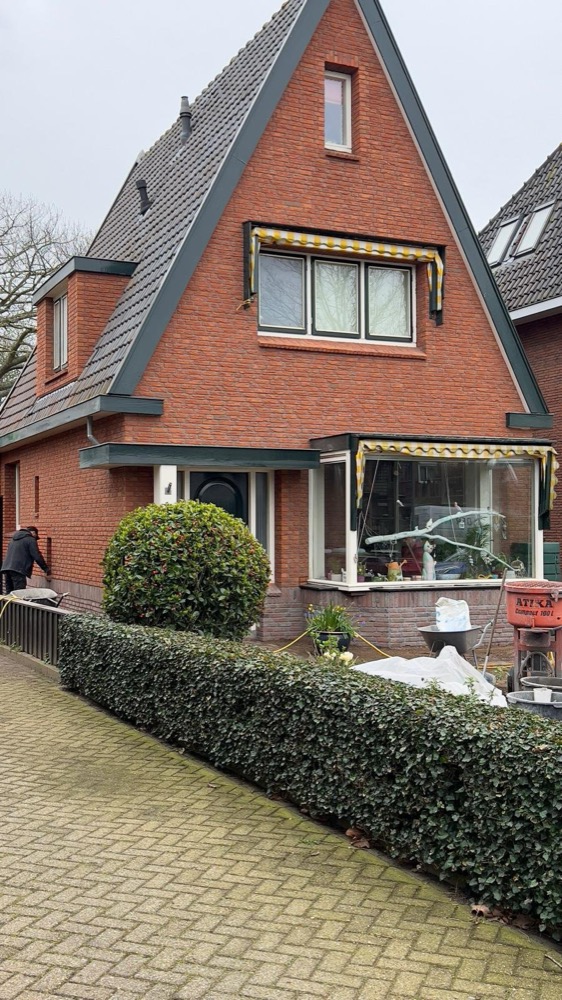 Voorgevel van het woonhuis in Heiloo met nieuwe rood-oranje steenstrips en bouwmaterialen bij de erker