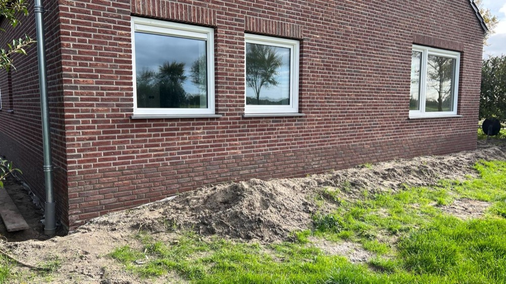Lange gevel met donkerrode steenstrips en drie kozijnen in Langedijk