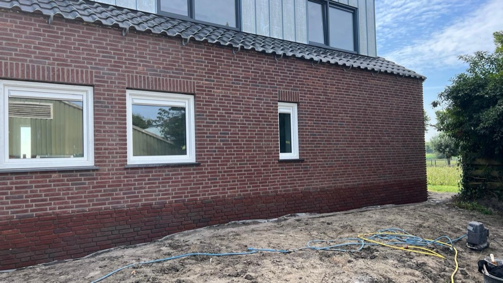 Aanbouw in Langedijk met steenstrips, witte kozijnen en een grijze bovenbouw