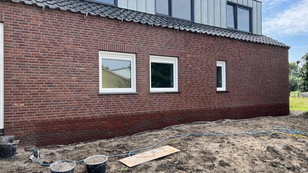 Rode steenstrips-gevel met wit raamkozijn bij een woonhuis in Langedijk